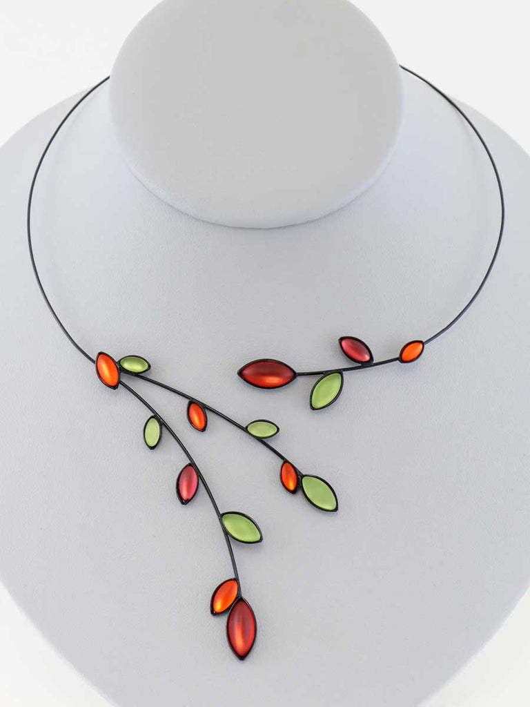 Necklace with green and red glass beads on a gray display
