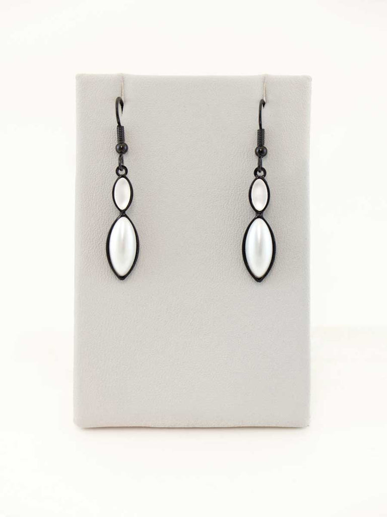 A pair of white pearl glass bead earrings on a gray display