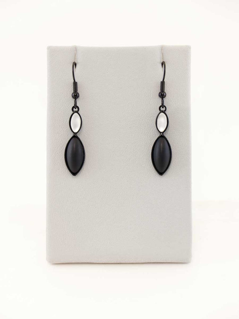 A pair of black and white glass bead earrings on a gray display