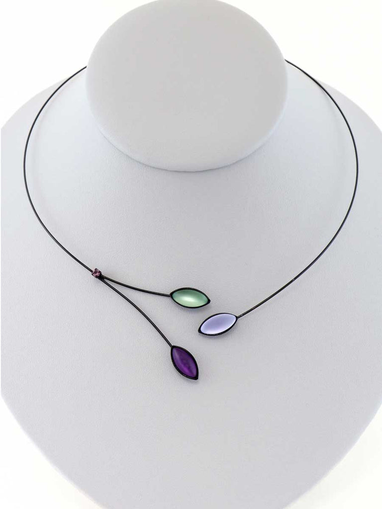 Necklace with green and purple glass beads on a gray display