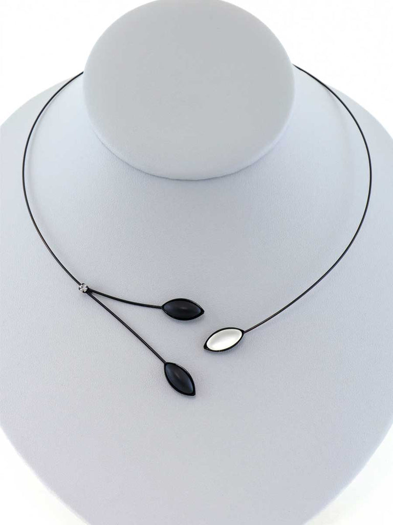Necklace with black and white glass beads on a gray display