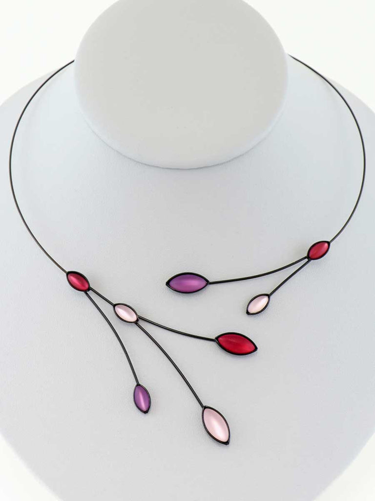 Necklace with pink and purple glass beads on a gray display