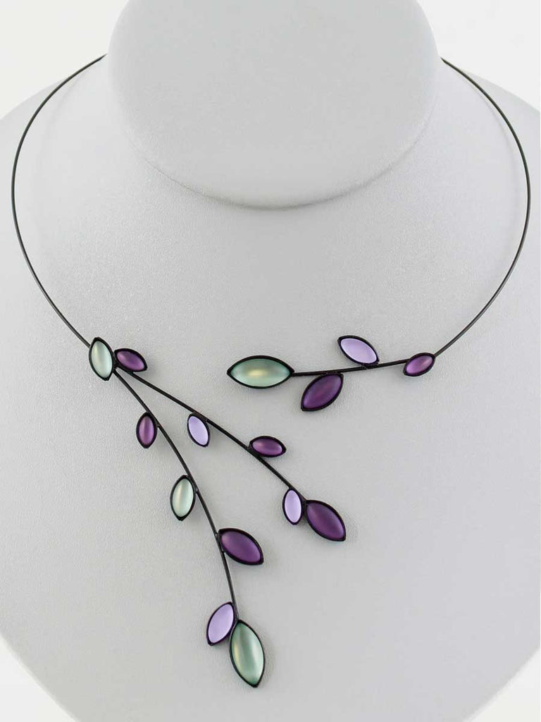 Necklace with green and purple glass beads on a gray display