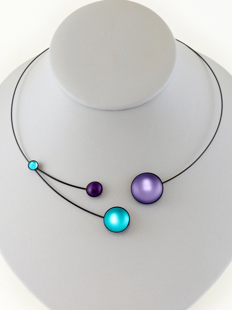 Necklace with purple and aqua glass beads on a gray display