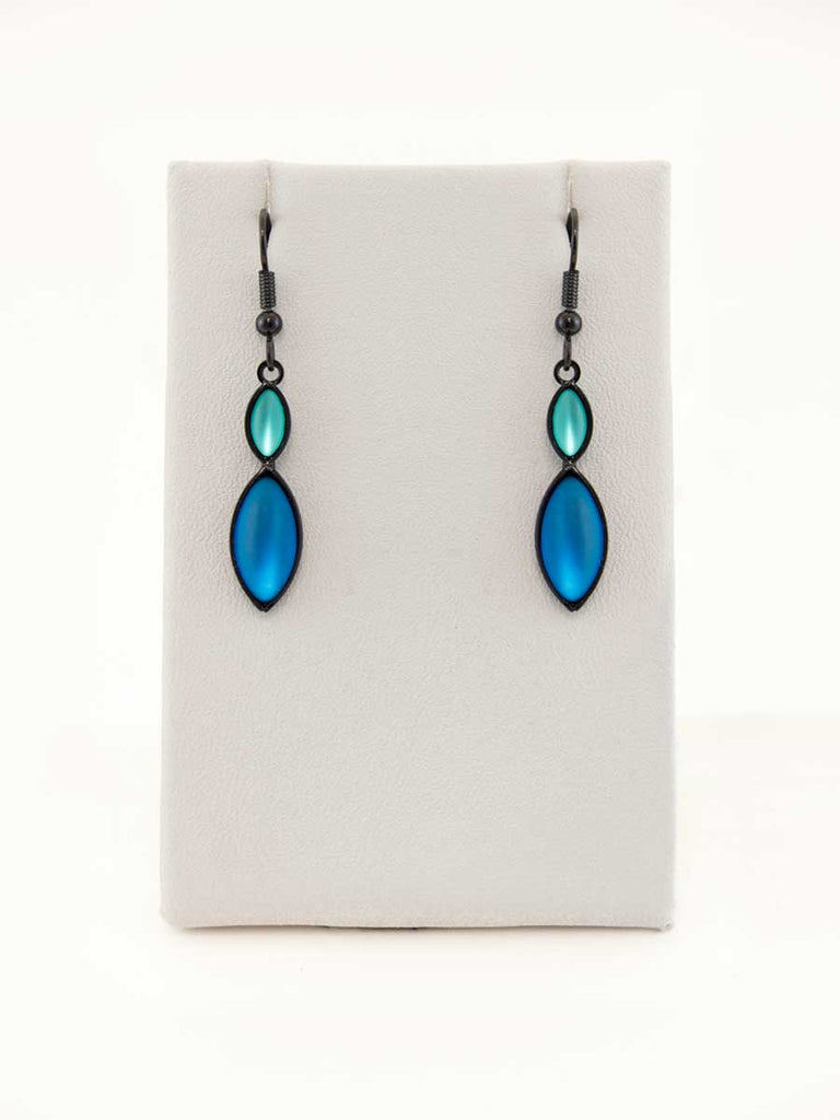 A pair of blue and green glass bead earrings on a gray display