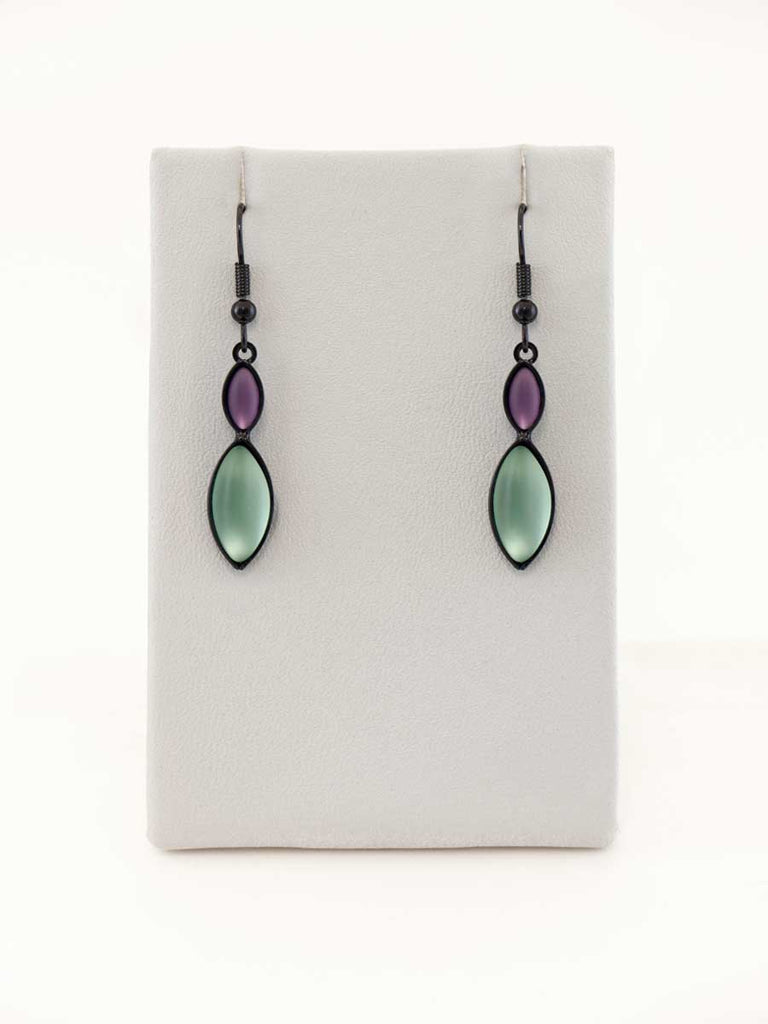 A pair of purple and green glass bead earrings on a gray display